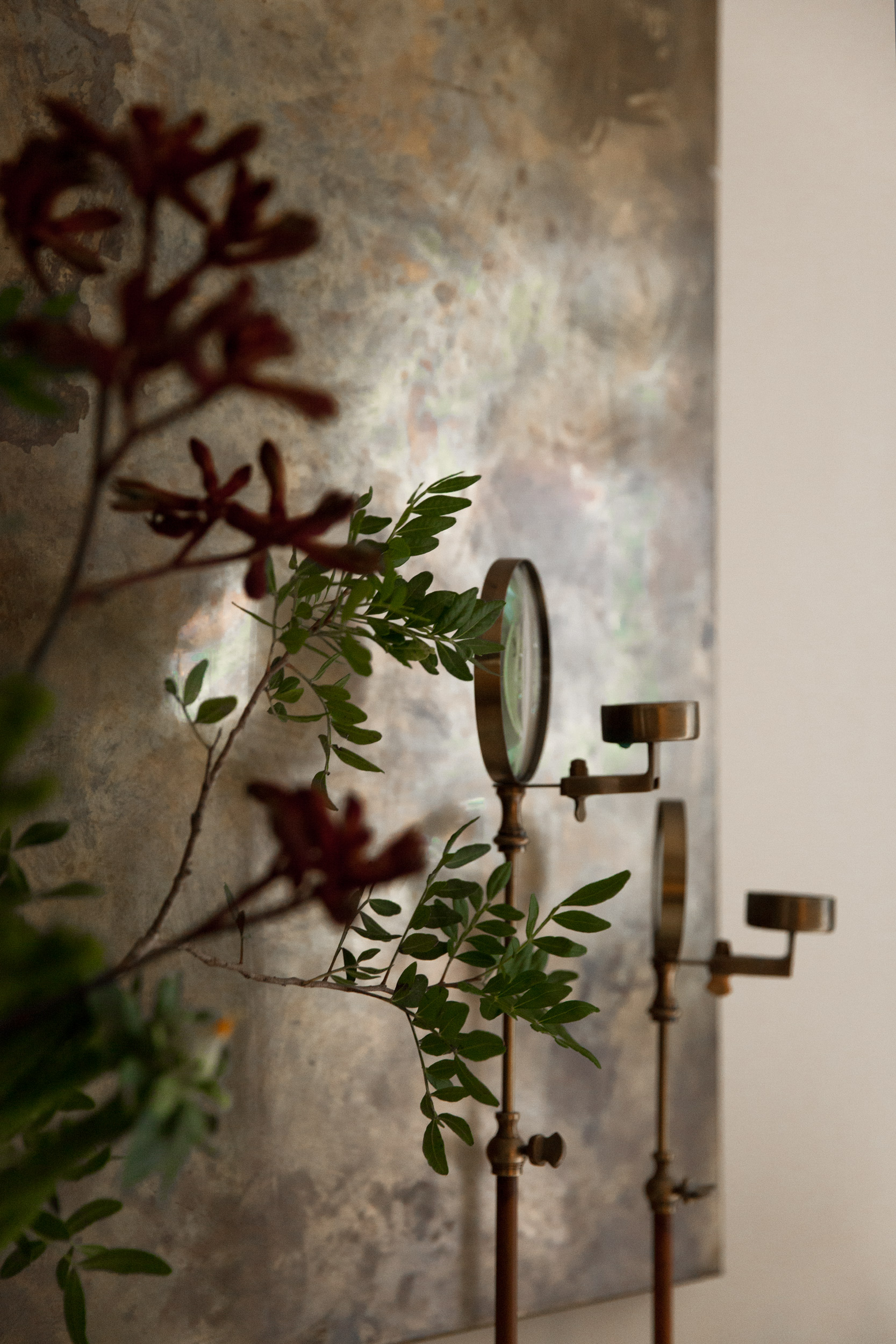 Flowers and brass candlesticks against textured artwork