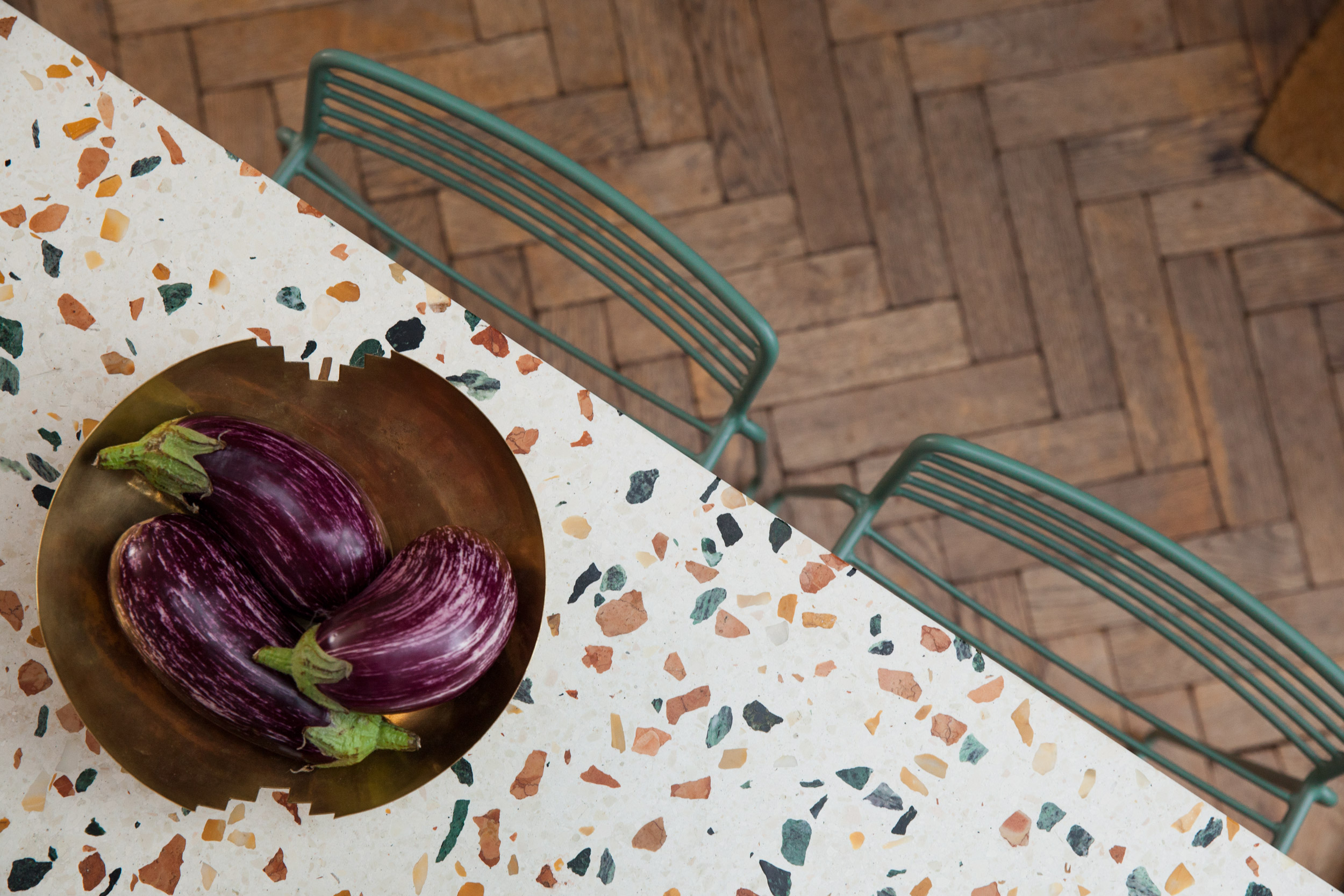 Terrazzo tabletop, green chairs and herringbone flooring