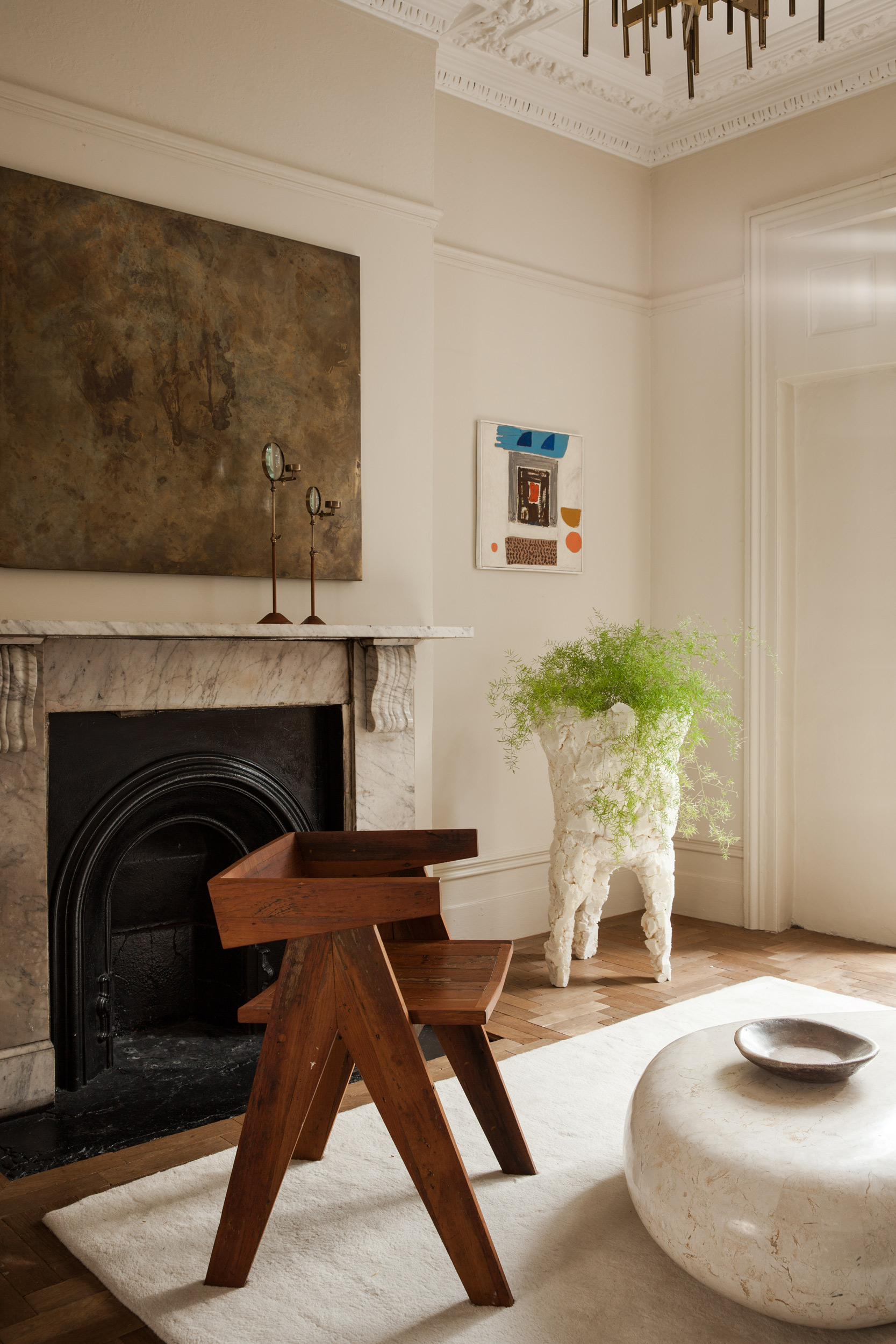 Marble fireplace with abstract art and a timber chair