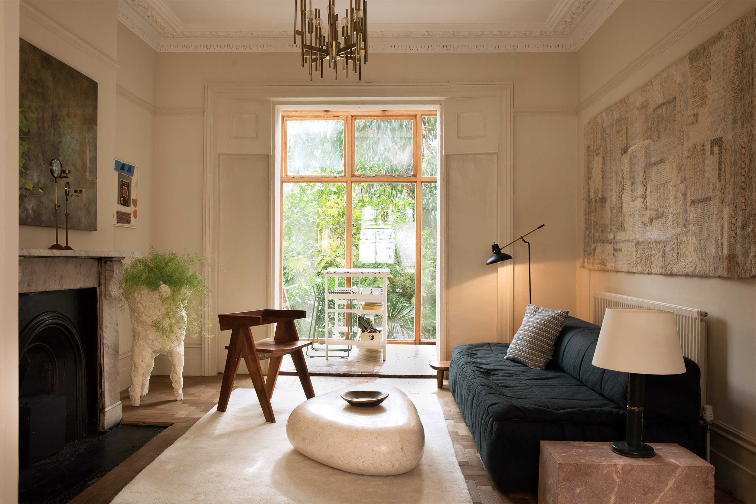 Ferndale living room with a dark sofa, sculptural coffee table and views into the glazed kitchen
