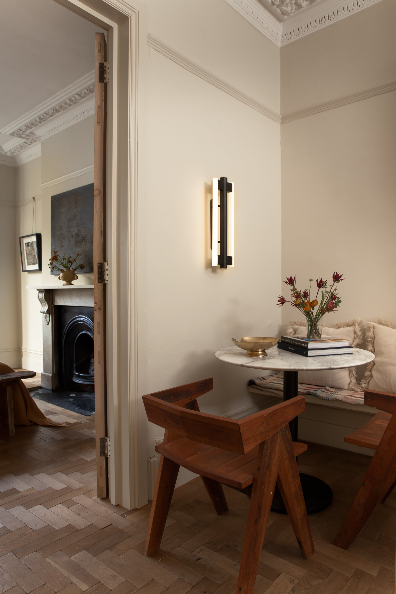 Intimate dining corner with timber chairs and wall lighting