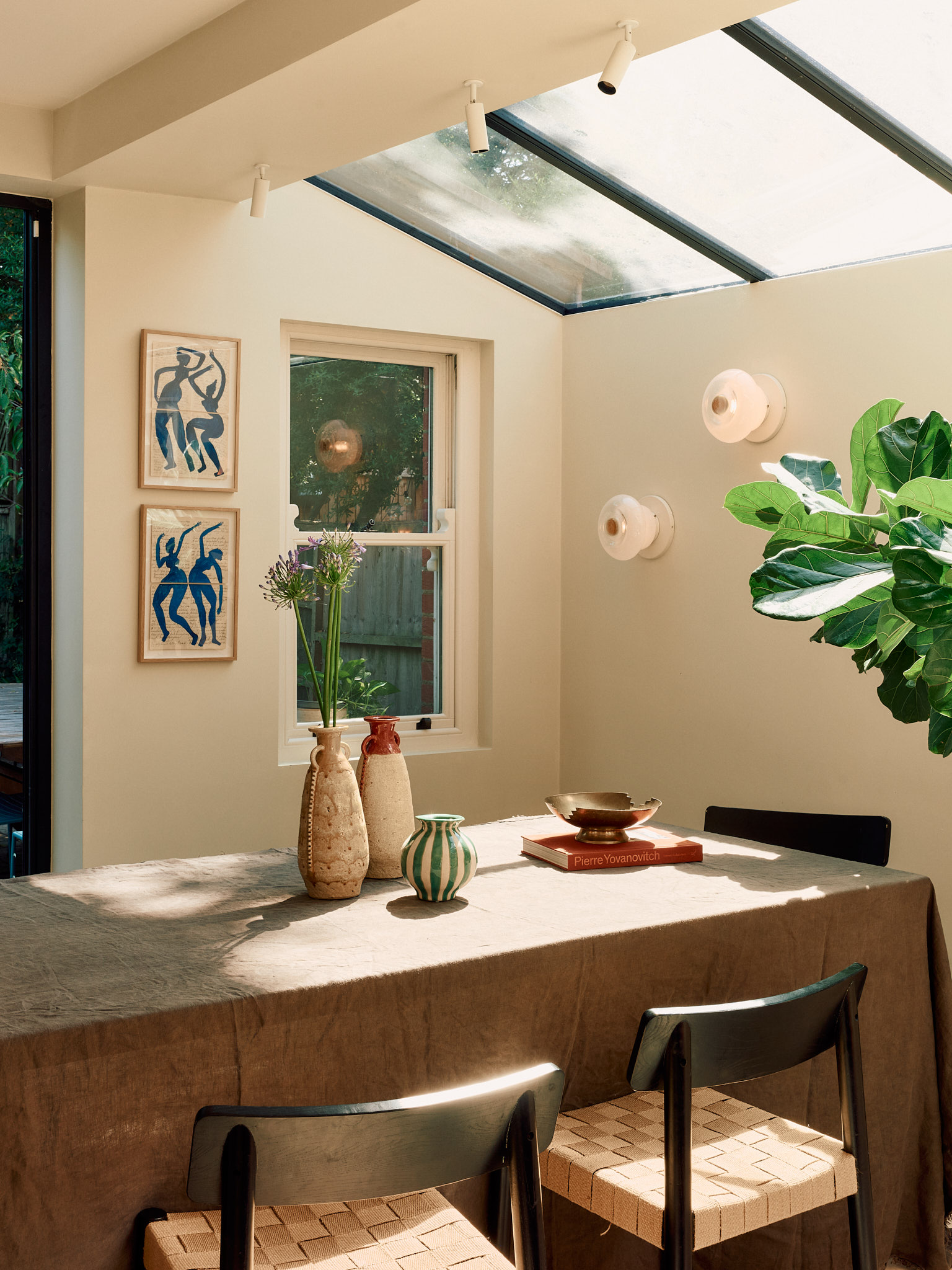 Dining table beside the garden with sculptural wall lights at School House