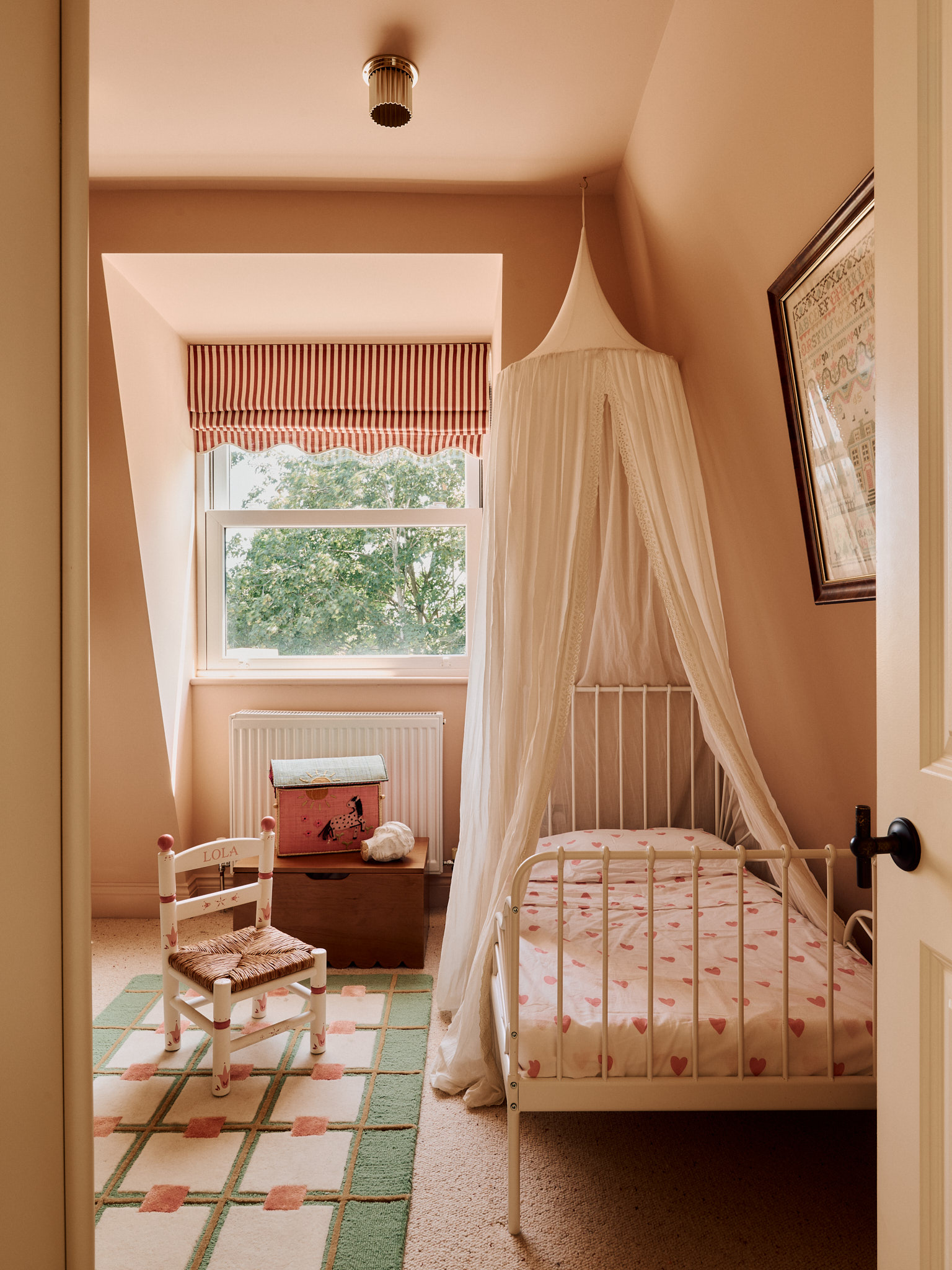 Pink bedroom with a canopy bed and patterned rug at School House