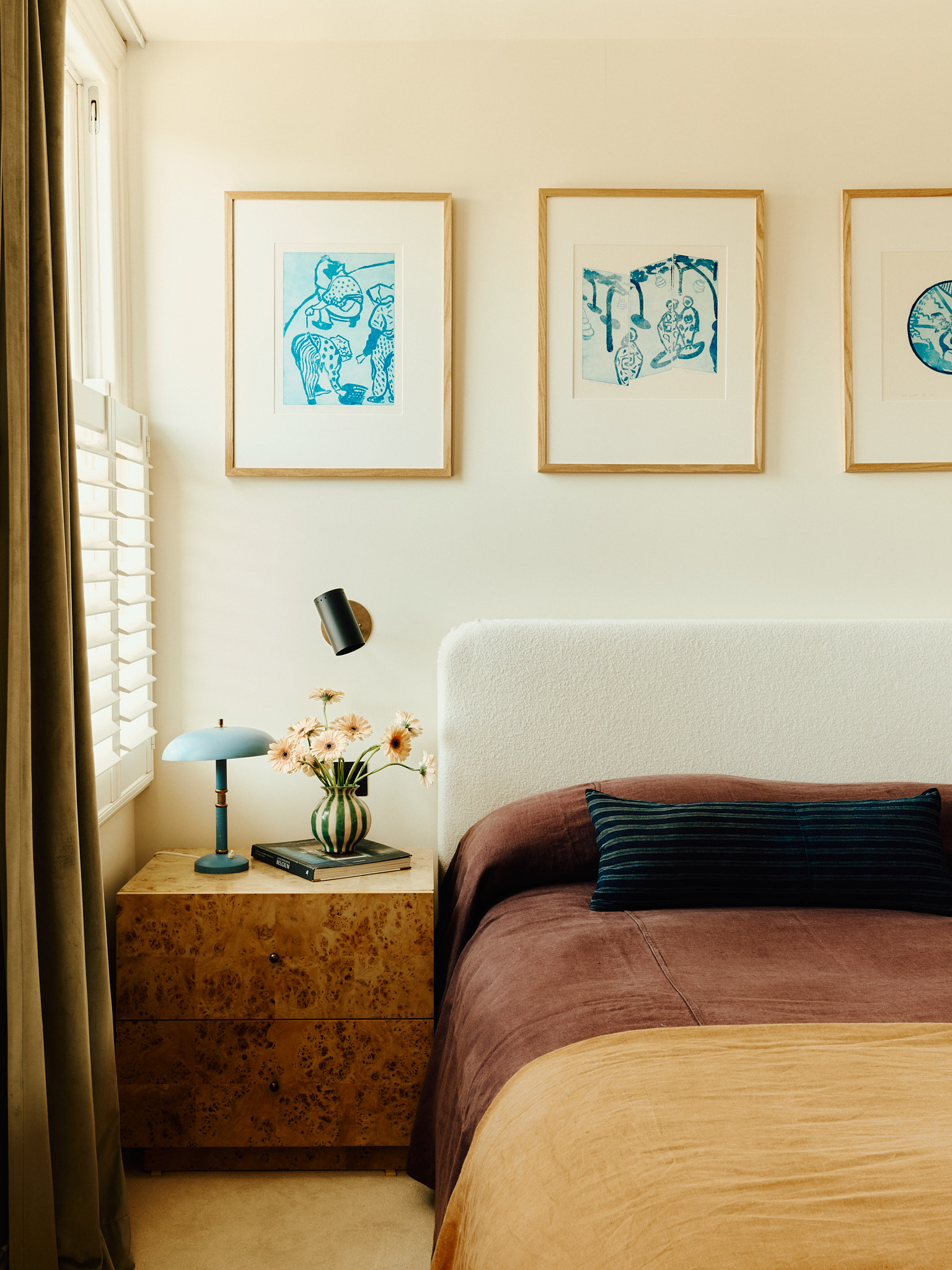 Bedroom with warm brown bedding, upholstered headboard and blue prints at School House