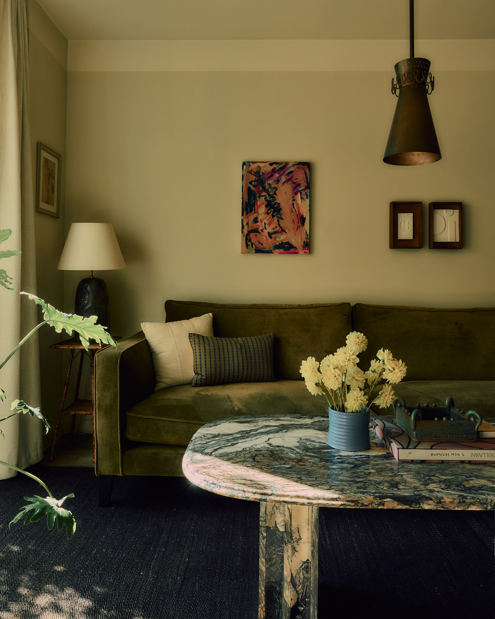 Olive sofa and sculptural stone table in the Wintergreen living room