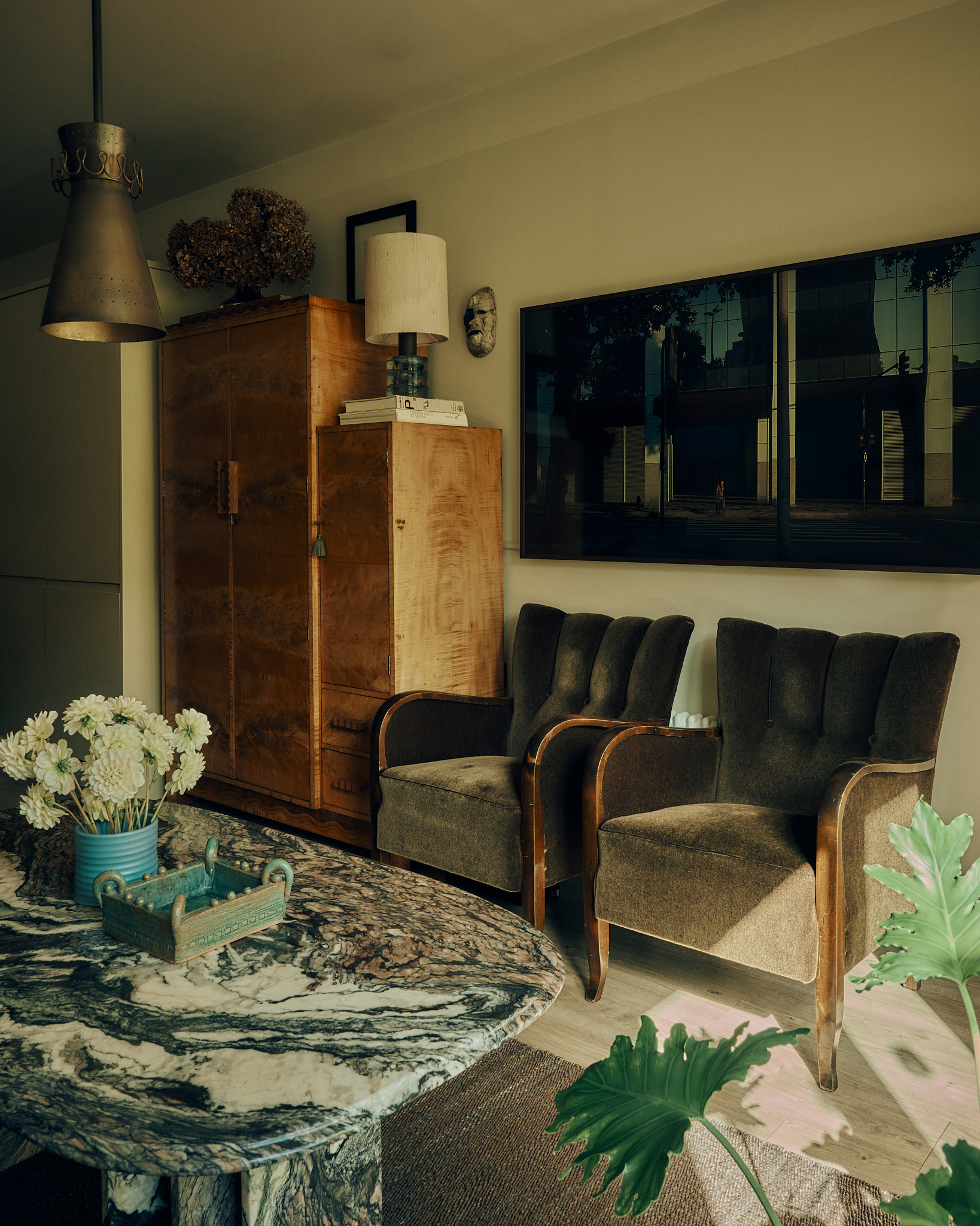 Period armchairs, collected art and warm timber
